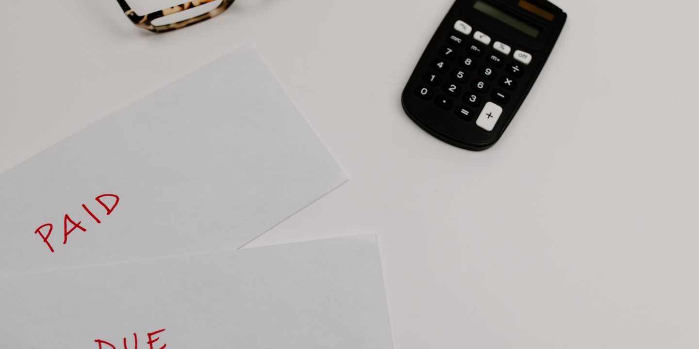 Dokumenty z adnotacjami "PAID" i "DUE" obok kalkulatora