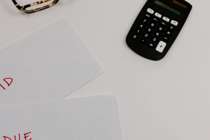 Dokumenty z adnotacjami "PAID" i "DUE" obok kalkulatora