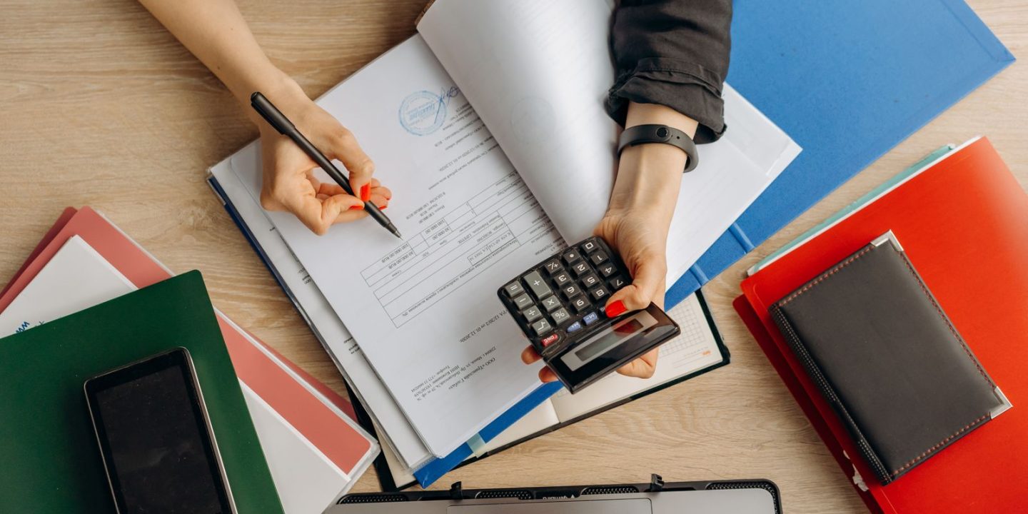 Dłonie z kalkulatorem nad dokumentami finansowymi