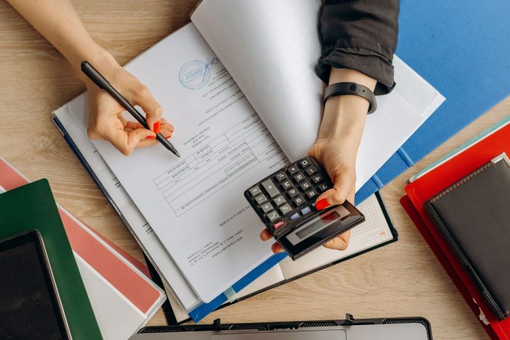 Dłonie z kalkulatorem nad dokumentami finansowymi