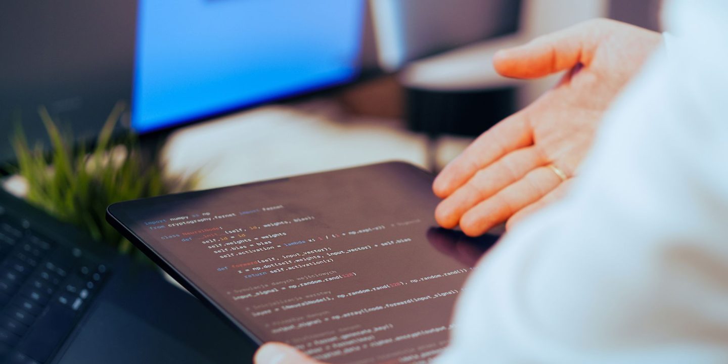 Programista obserwujący działanie agenta AI na ekranach z kodem i logami