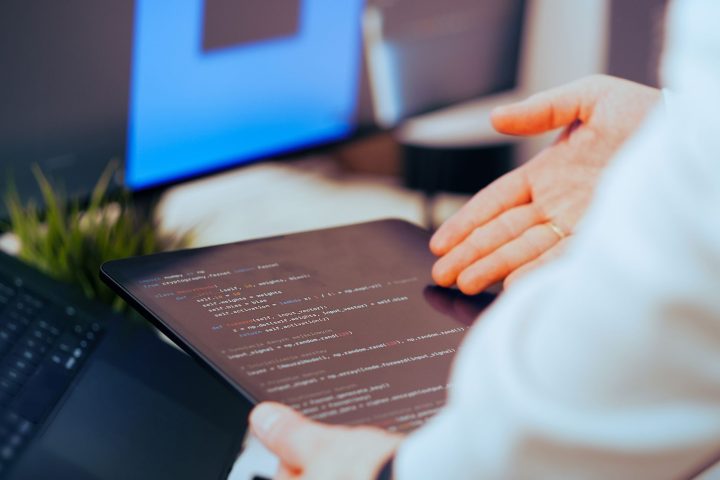 Programista obserwujący działanie agenta AI na ekranach z kodem i logami