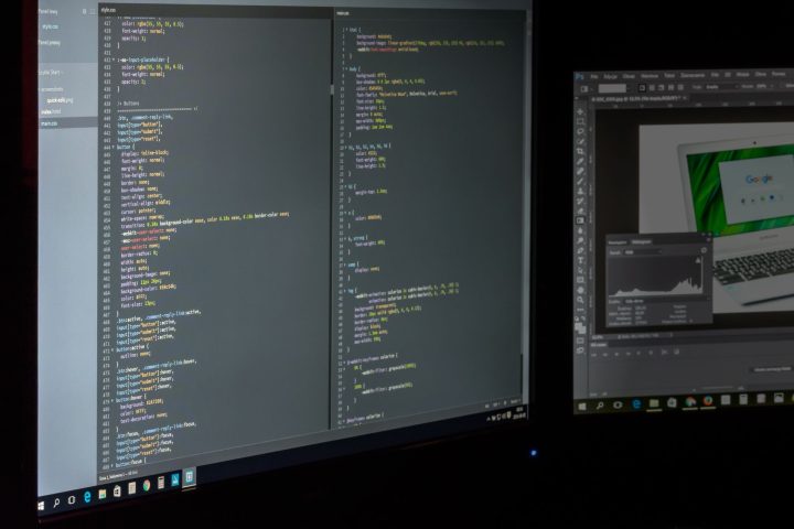 Programista pracujący przy dwóch monitorach z otwartym kodem źródłowym