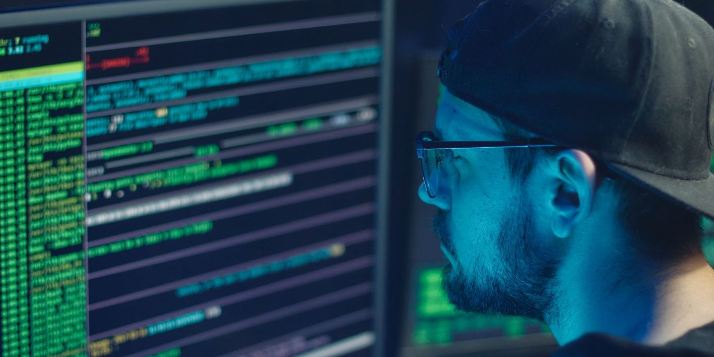 Specjalista do spraw cyberbezpieczeństwa analizujący kod na monitorach