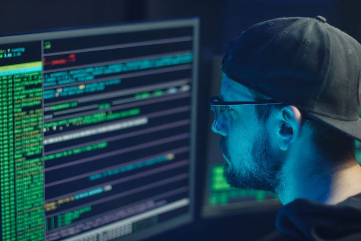 Specjalista do spraw cyberbezpieczeństwa analizujący kod na monitorach