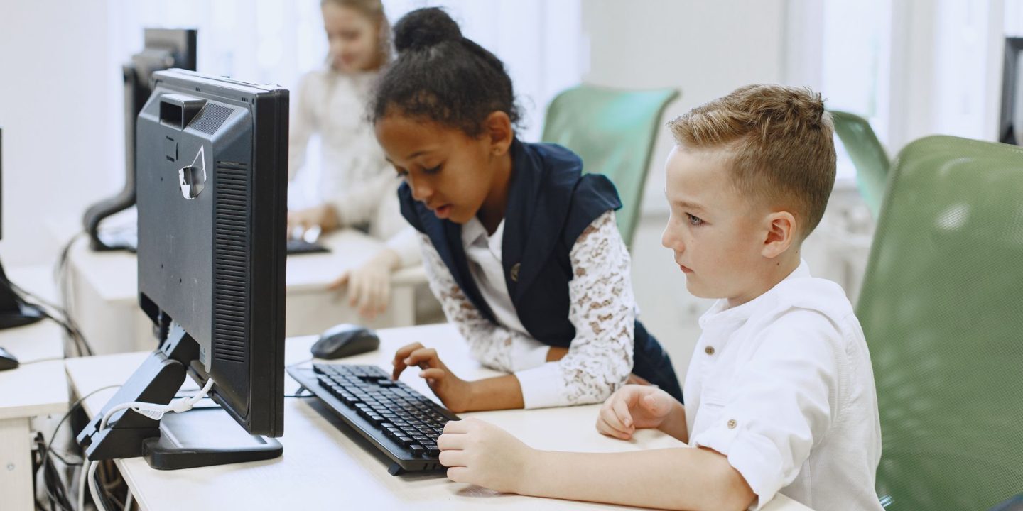 Uczniowie pracujący przy komputerach podczas zajęć w klasie