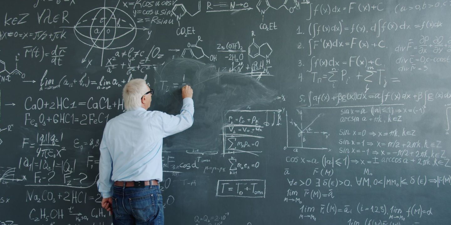 Matematyk sprawdzający równania i zapisany dowód na tablicy