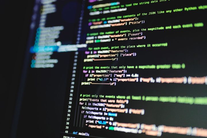 Programista analizujący starszy kod źródłowy na kilku monitorach