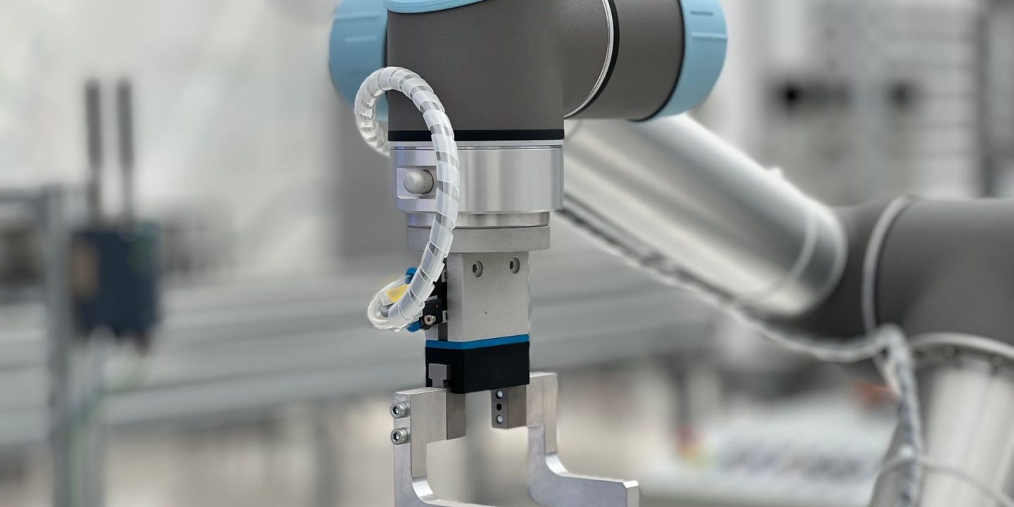 Robotyczna dłoń pracująca przy linii produkcyjnej w fabryce